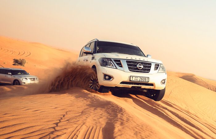 Sunrise over the sand dunes in Al Awir during a morning desert safari, featuring a desert adventurer sandboarding down a dune